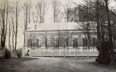 <p>Foto van voor 1891 van de houten concertzaal uit 1868. Het terrein van de Buitensociëteit is van de weg afgescheiden door middel van een houten hekwerk (Looper 1991). </p>
